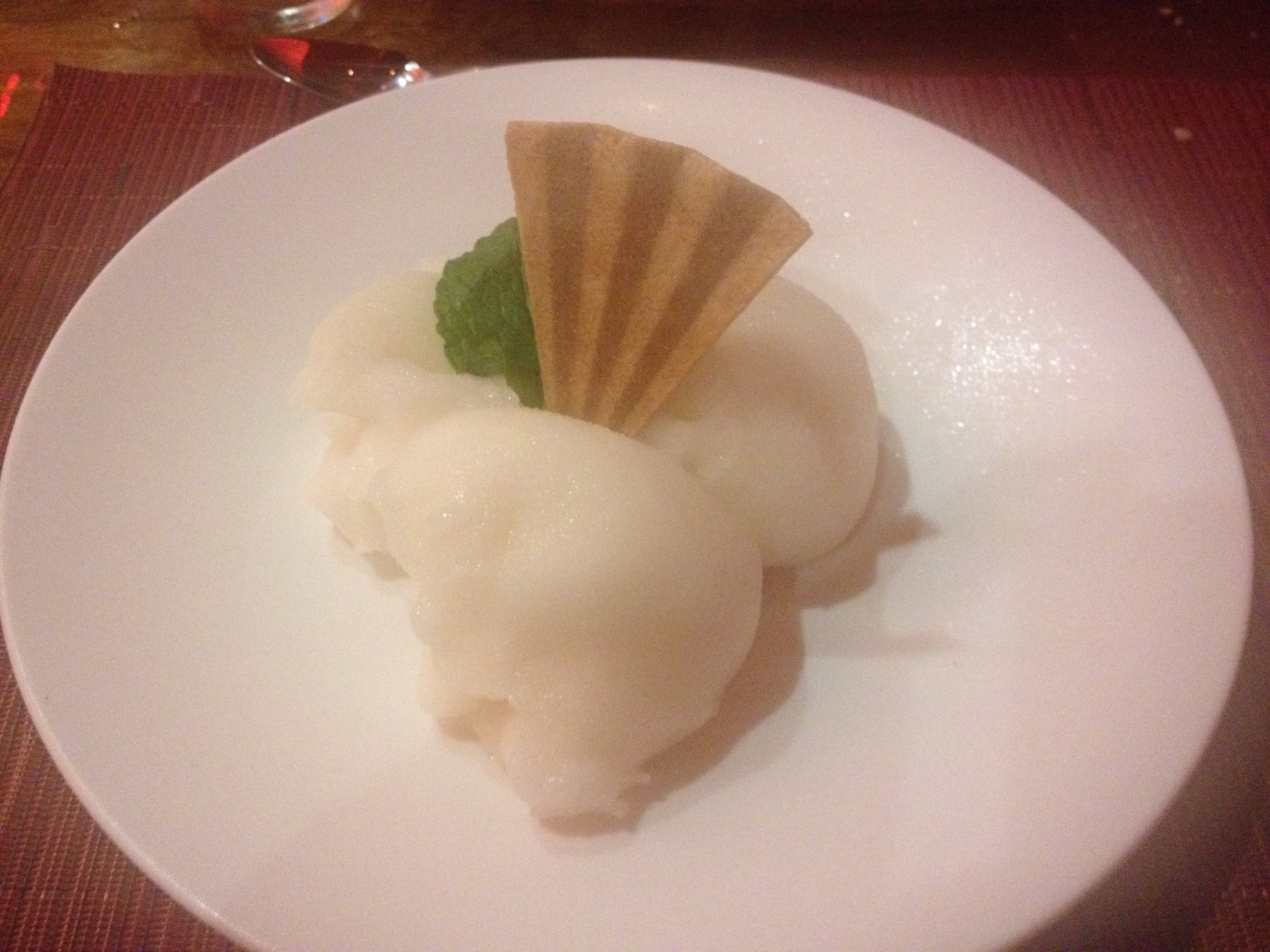 Three scoops of pale sorbet with a wafer and mint leaf