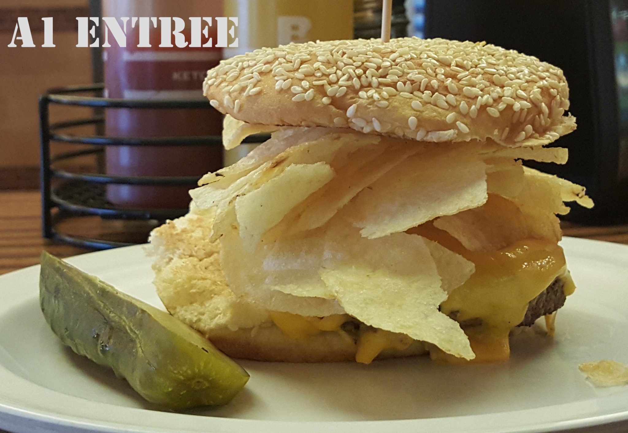 Cheeseburger with potato chips and a pickle on a plate