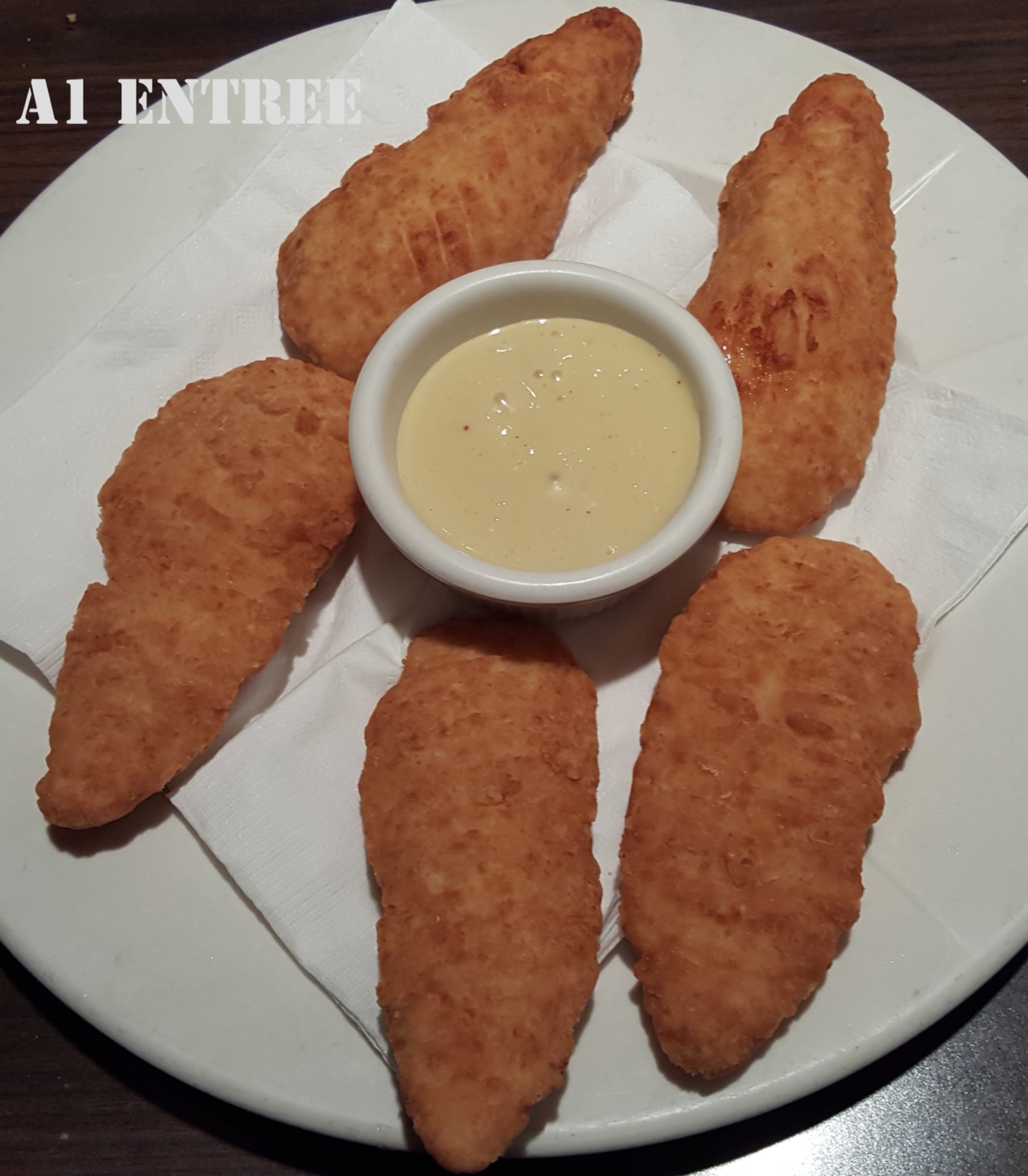 Chicken tenders arranged around dipping sauce